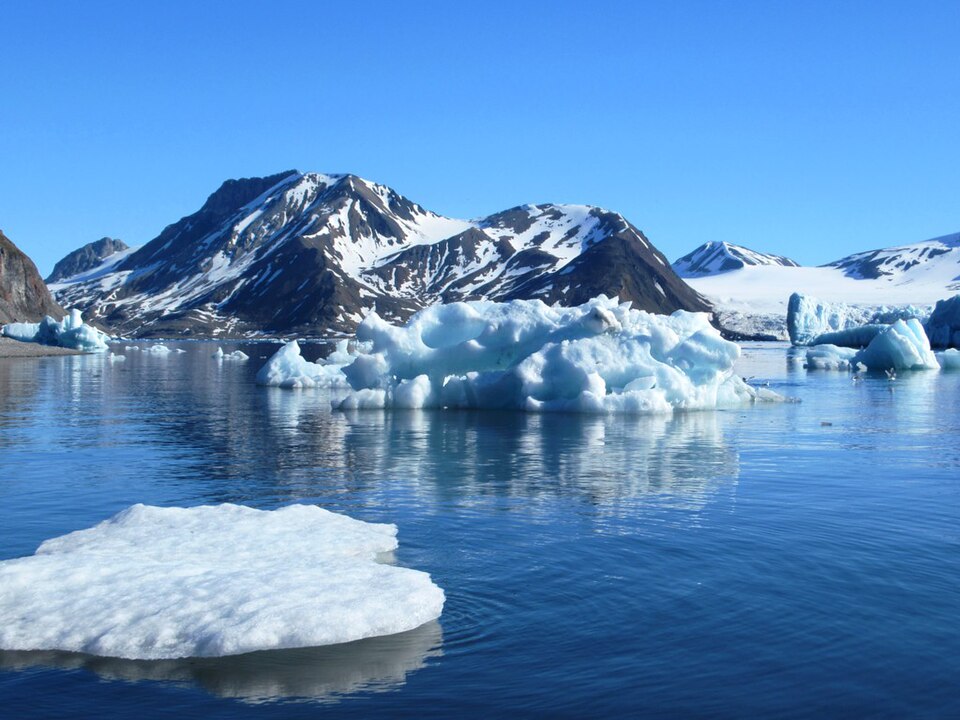 Icebergs floating below snow-covered mountains in Hornsund Fjord, Svalbard, in 2022