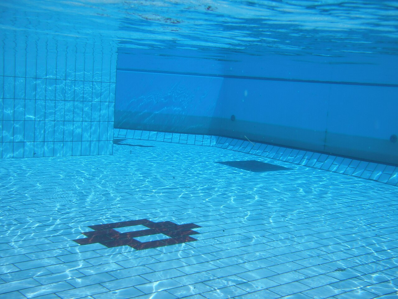 Underwater view of an unoccupied tiled swimming pool.