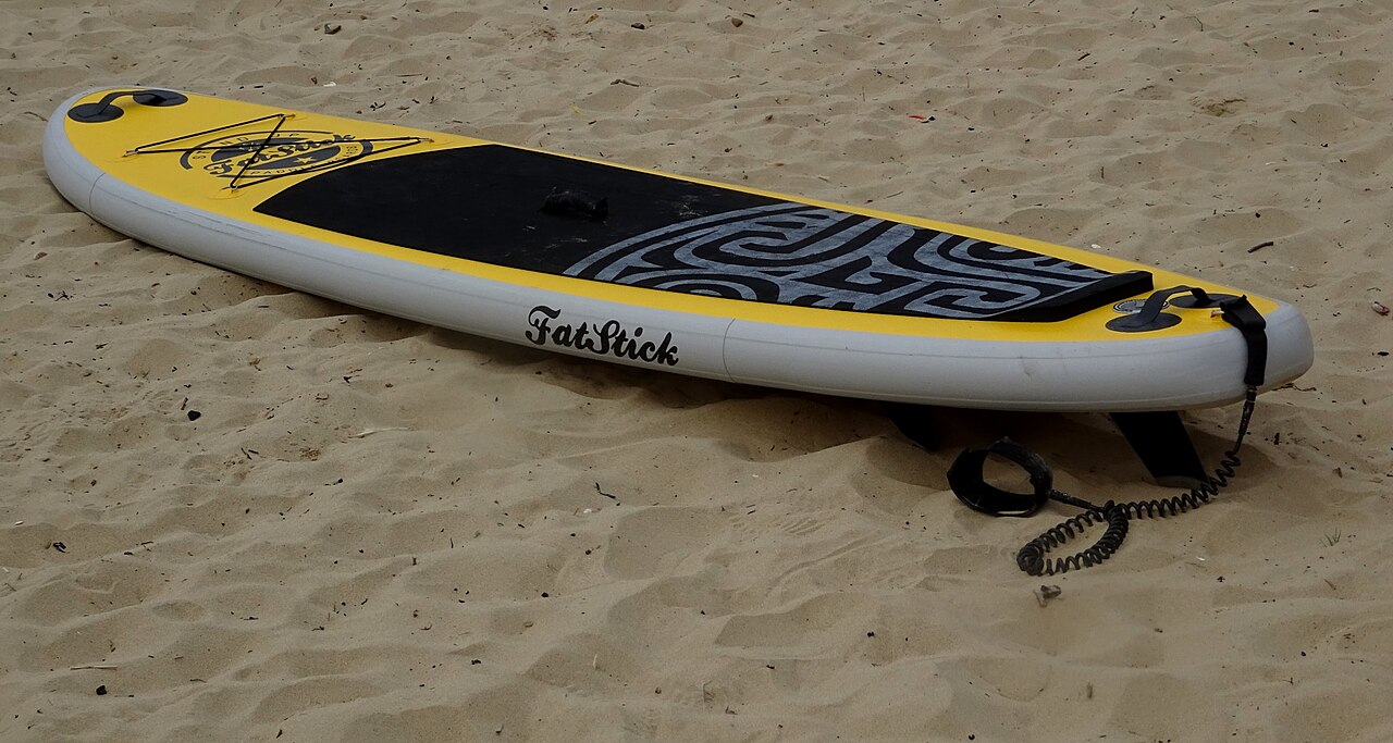 Yellow inflatable paddleboard resting on sand