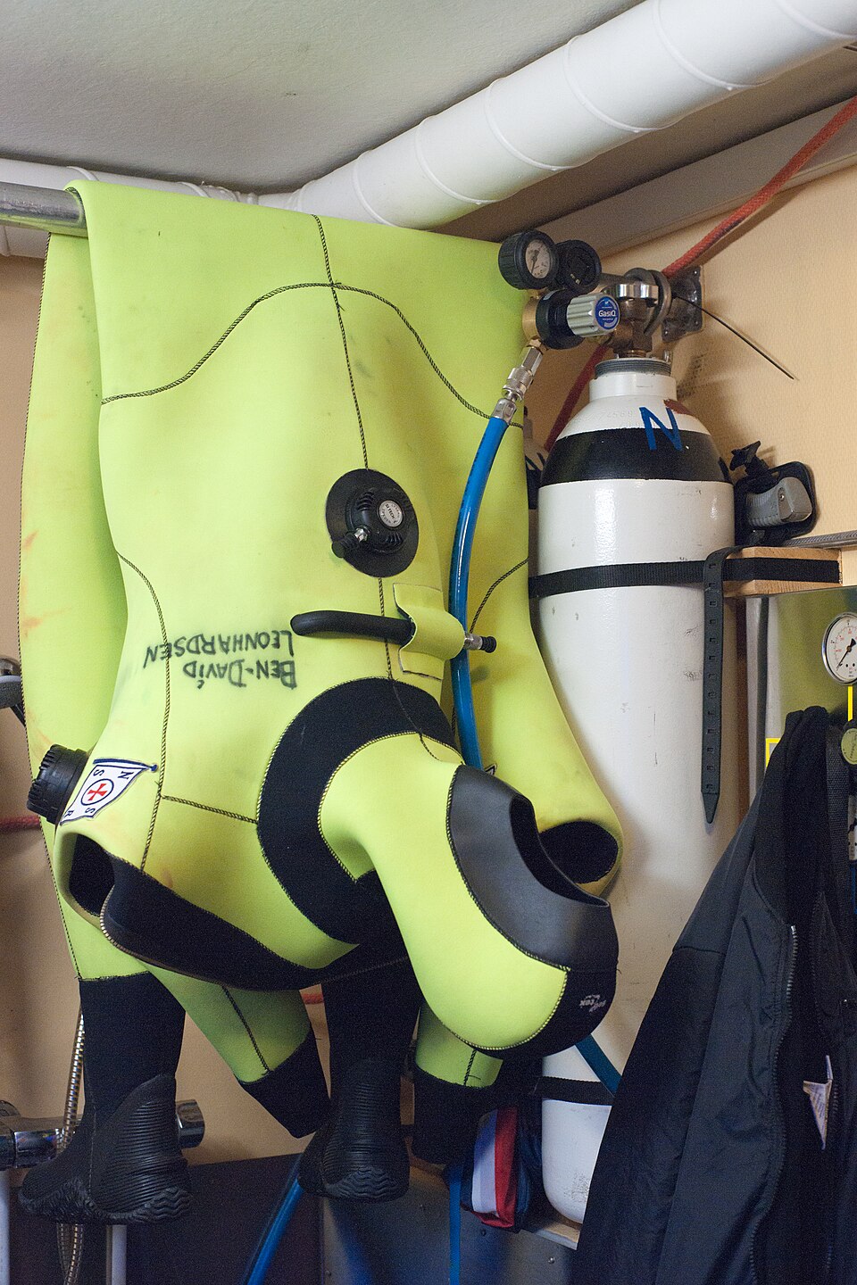 A yellow drysuit hanging beside diving cylinders aboard the SAR vessel Ulabrand