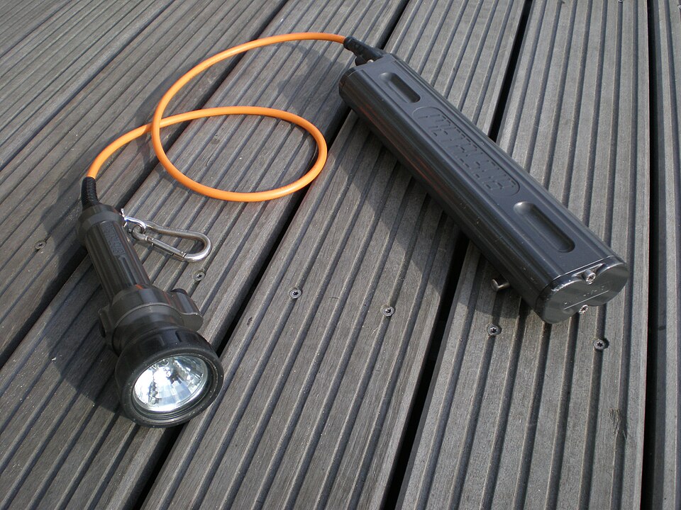 Historical Metalsub cable dive torch with a separate battery canister on a wooden surface
