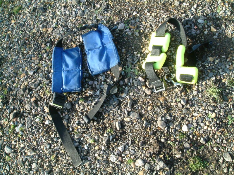 A blue pocket-style dive weight belt and a separate traditional belt with weights on gravel
