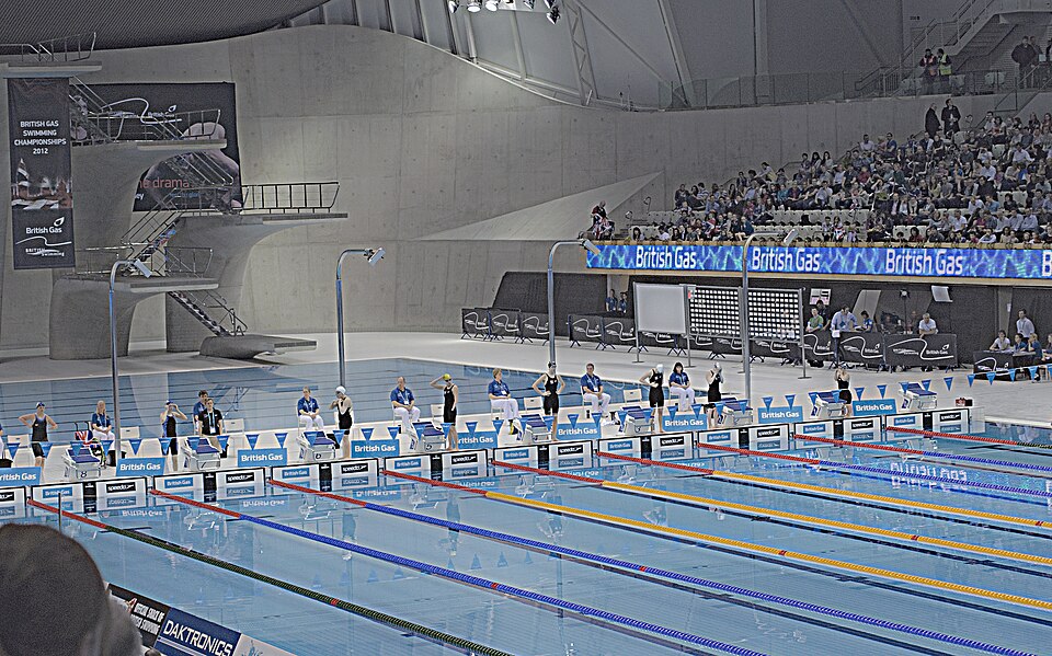Wide historical photograph of swimmers, officials and lanes at swimming time trials in Stratford, London, in March 2012, a different event from Nagoya.