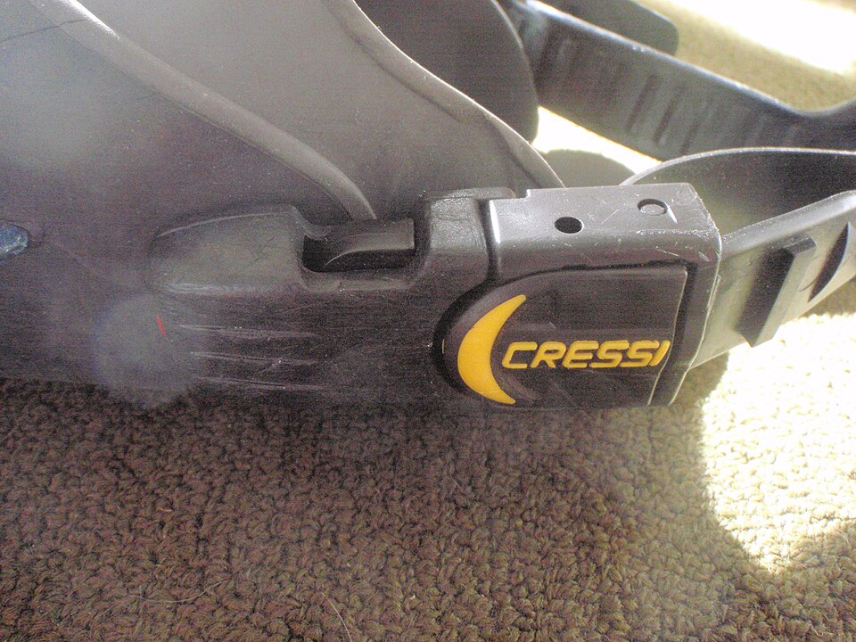 Close view of a plastic buckle and strap on an older open-heel Cressi fin