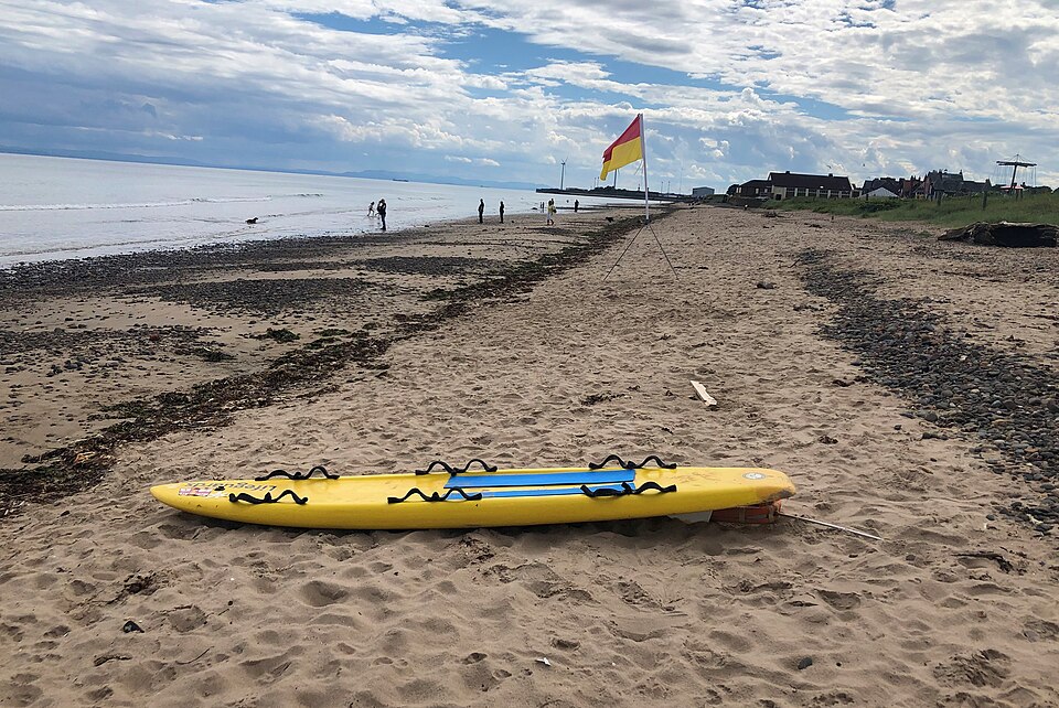 Yellow paddleboard resting on Leven Beach