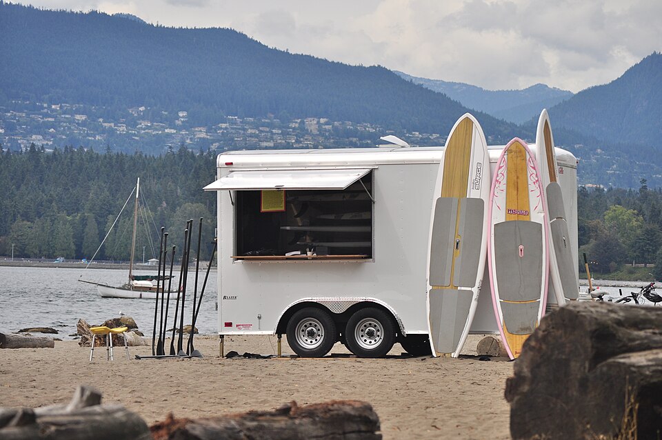 Stand-up paddleboards beside a beach rental trailer