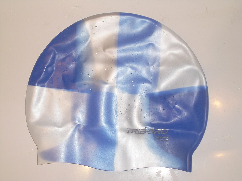 Real photograph of a blue and white silicone swimming cap lying flat, used as equipment context.