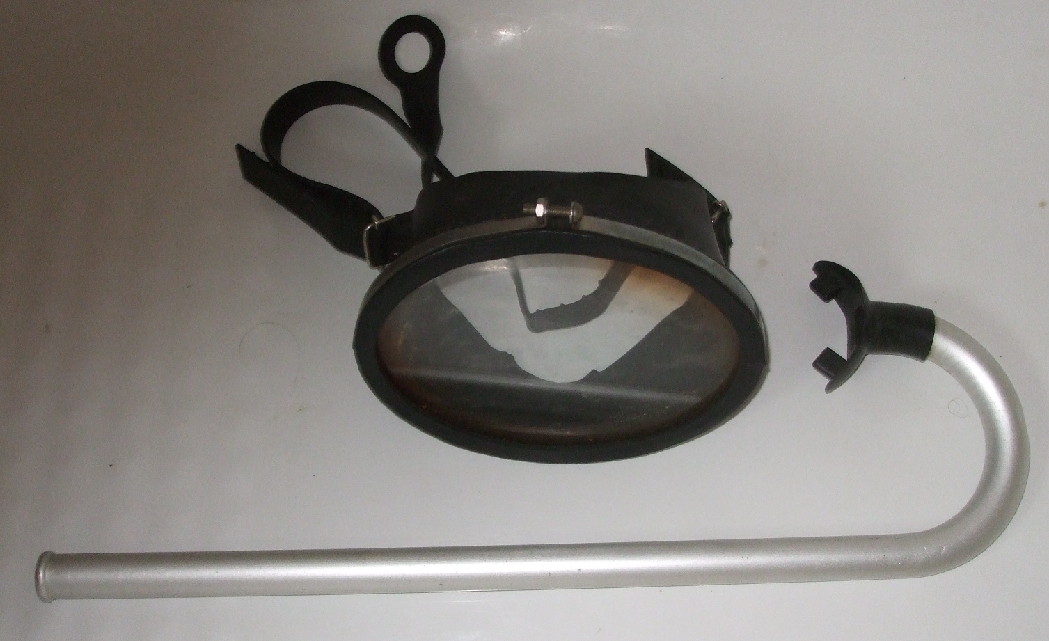 An older black mask beside a rigid curved snorkel tube