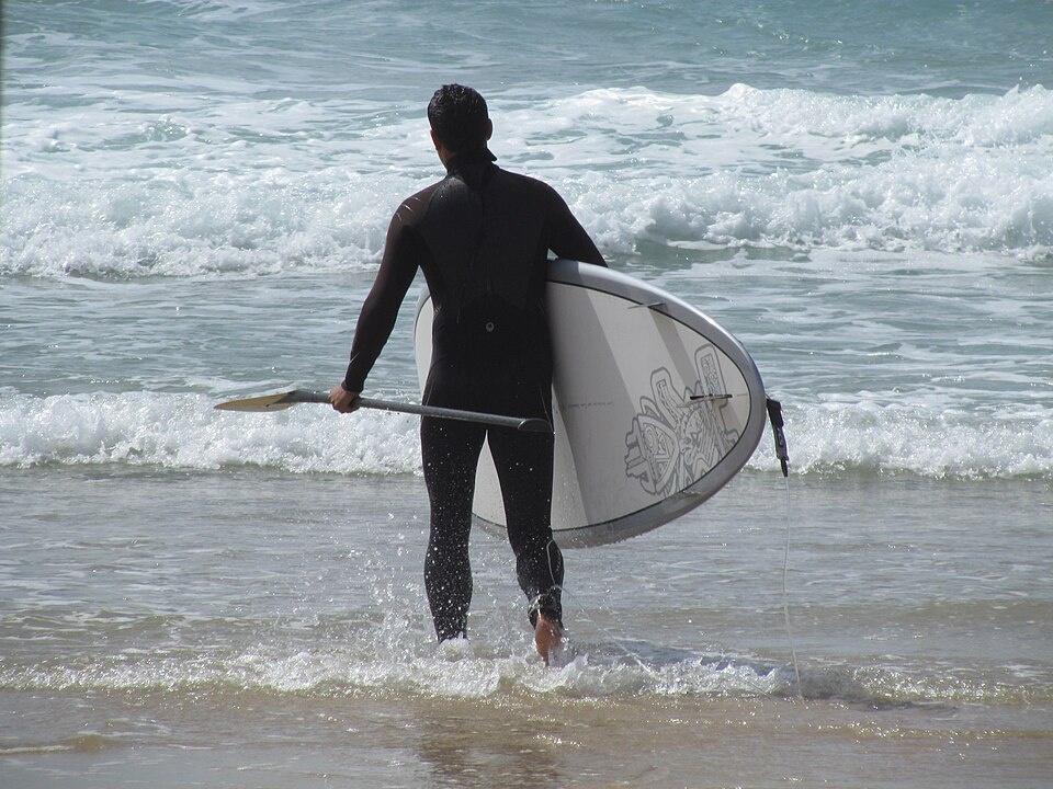 Paddler carrying a board toward the sea