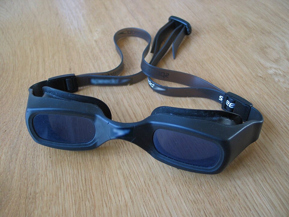 Archive blue swim goggles resting on a wooden surface, not a coating-care or performance test.