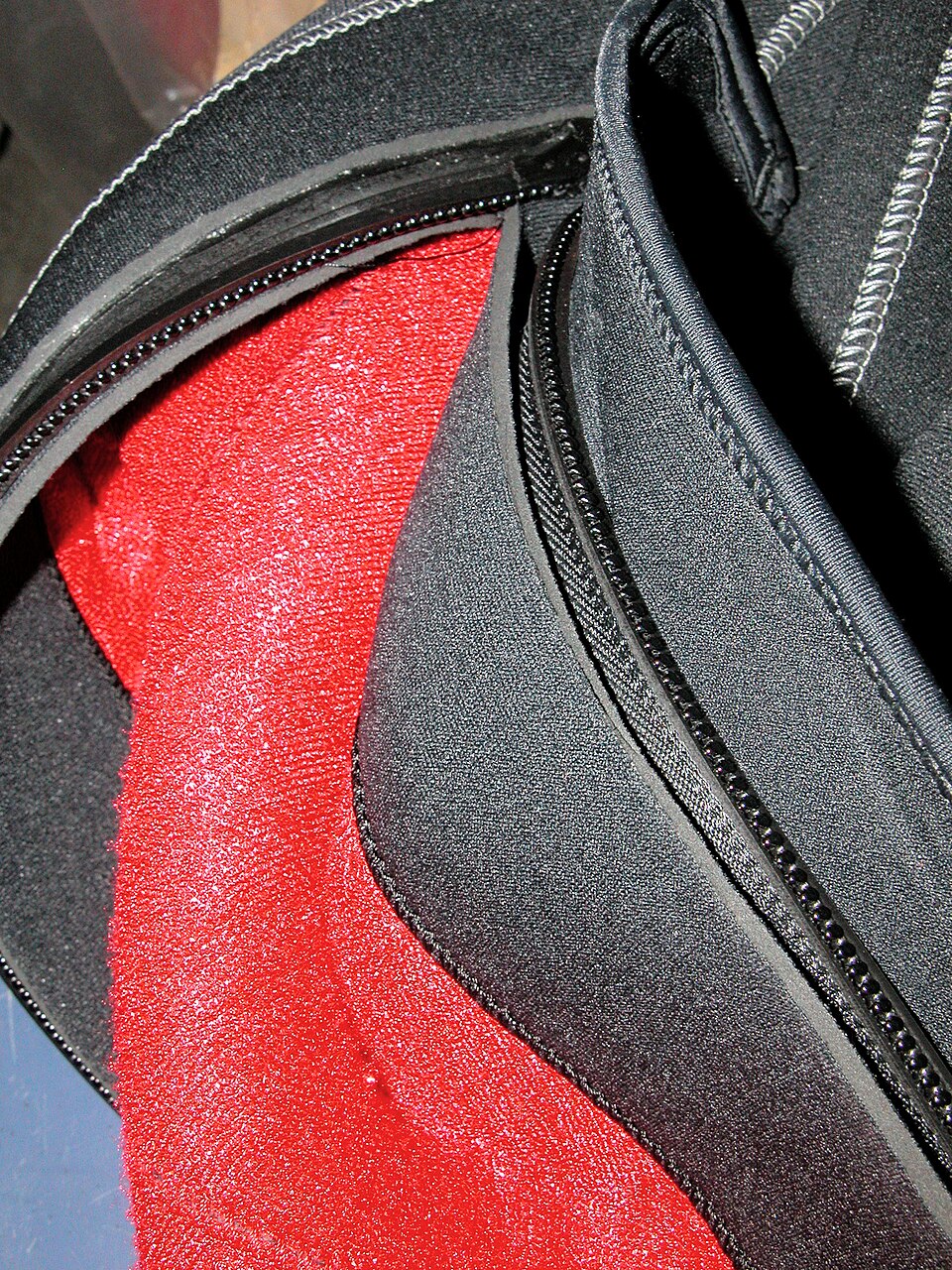 Close view of a wetsuit zipper beside its lining and protective flap