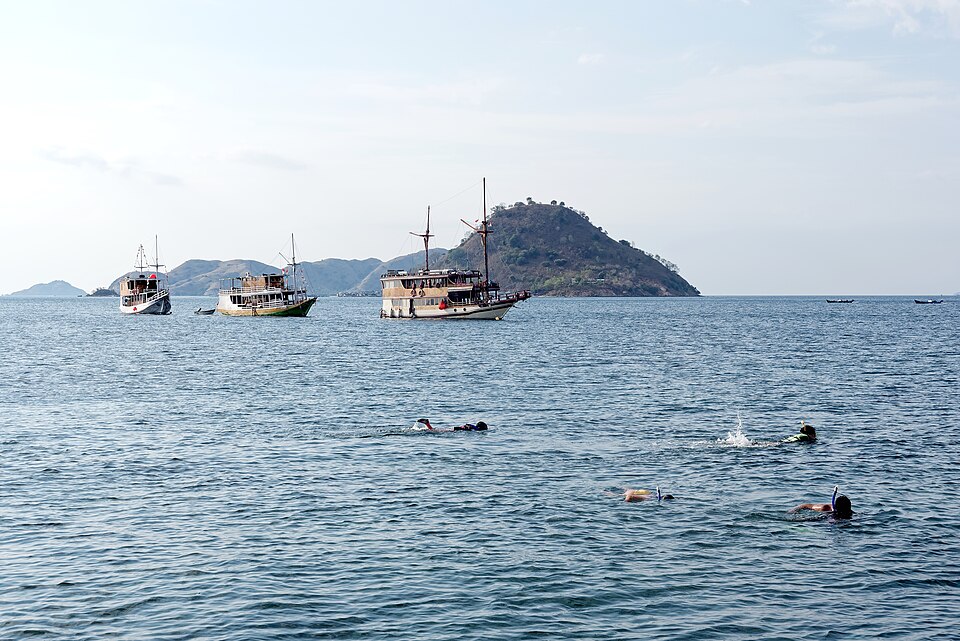 Distant snorkelers and boats in the sea near Manjarite Beach in Indonesia