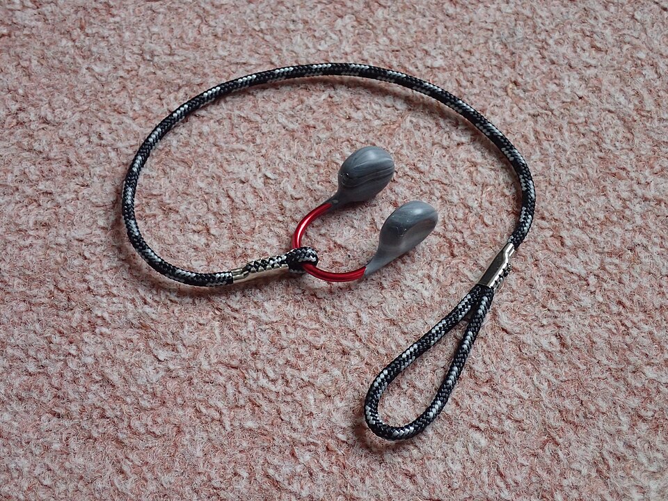 Archive wire nose clip with padded ends and a cord lying on a carpet.