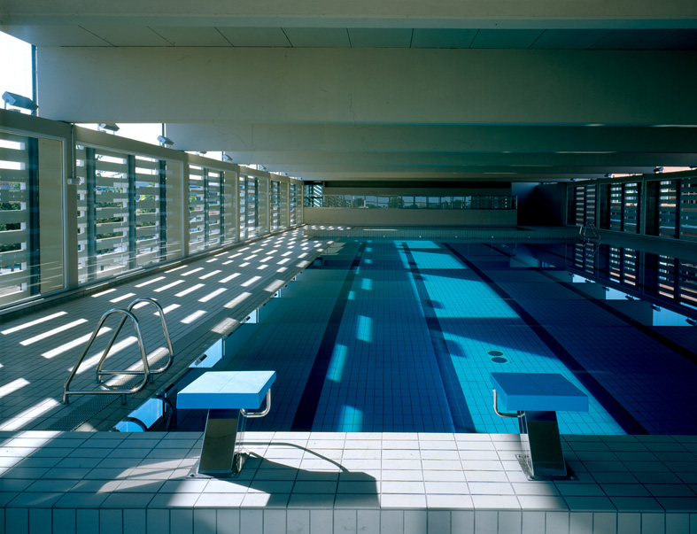 Archived photograph of an empty indoor swimming pool with lanes and starting blocks in San Fernando de Henares, Spain.