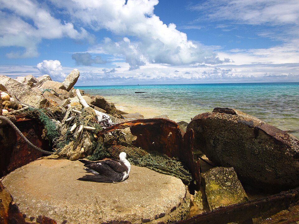 Derelict fishing gear among shoreline rocks on Midway Atoll beside the ocean