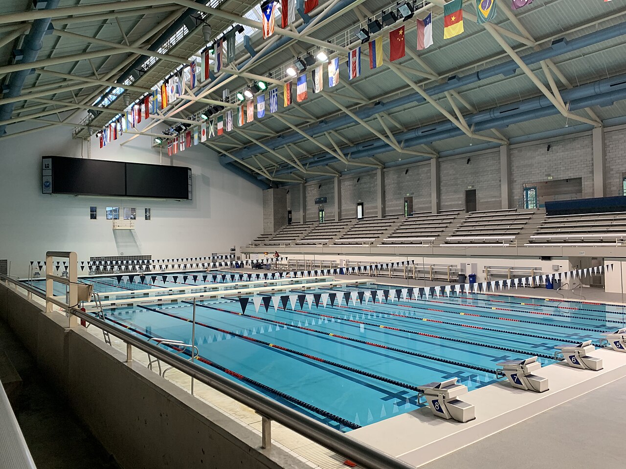 Competition swimming pool with lane ropes, spectator seating and timing scoreboard.